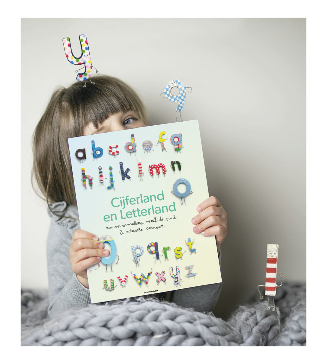 Kind houdt boek Cijferland en Letterland voor gezicht