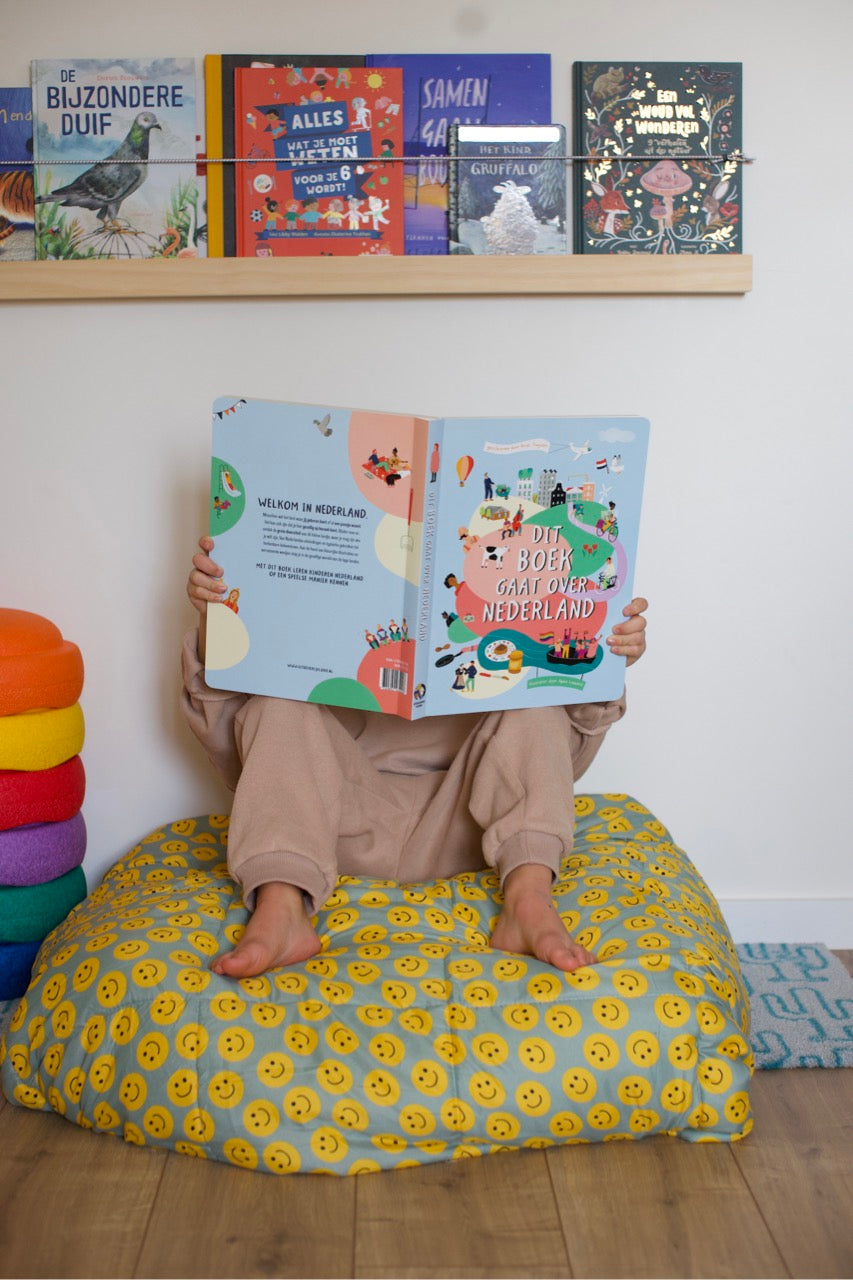 Kind houdt het boek Dit boek gaat over Nederland voor het gezicht